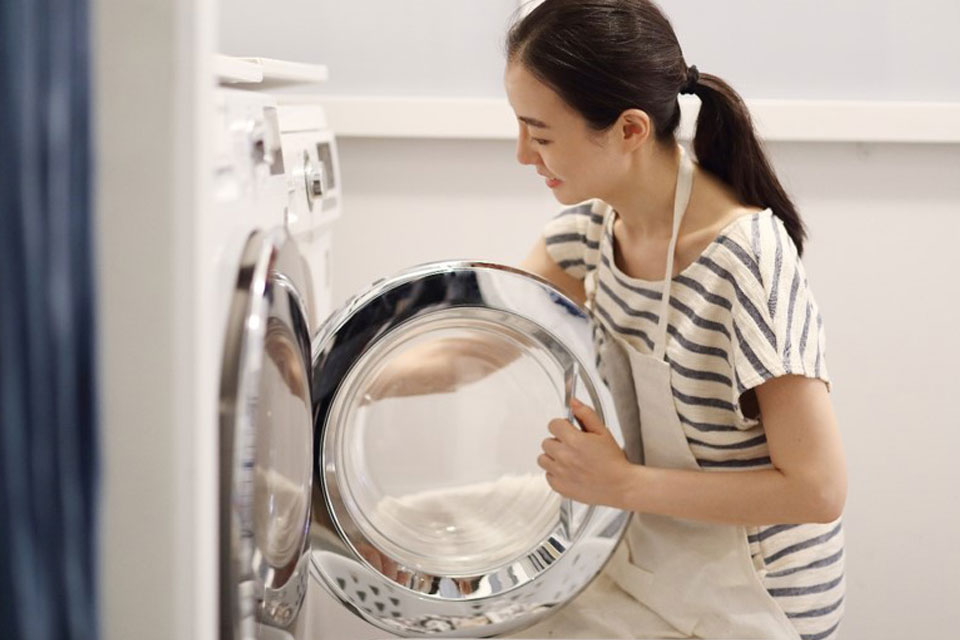 洗濯機から洗濯物を出す女性の写真